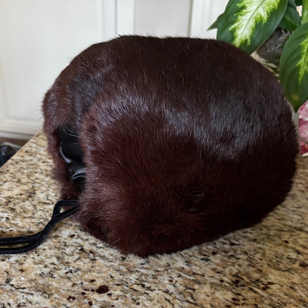 Dark brown fur muff with satin lining and a velvet strap.  Like new…barely used